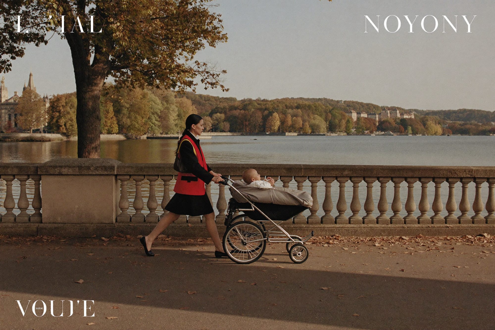 A nanny pushing a pram along a lakeside promenade