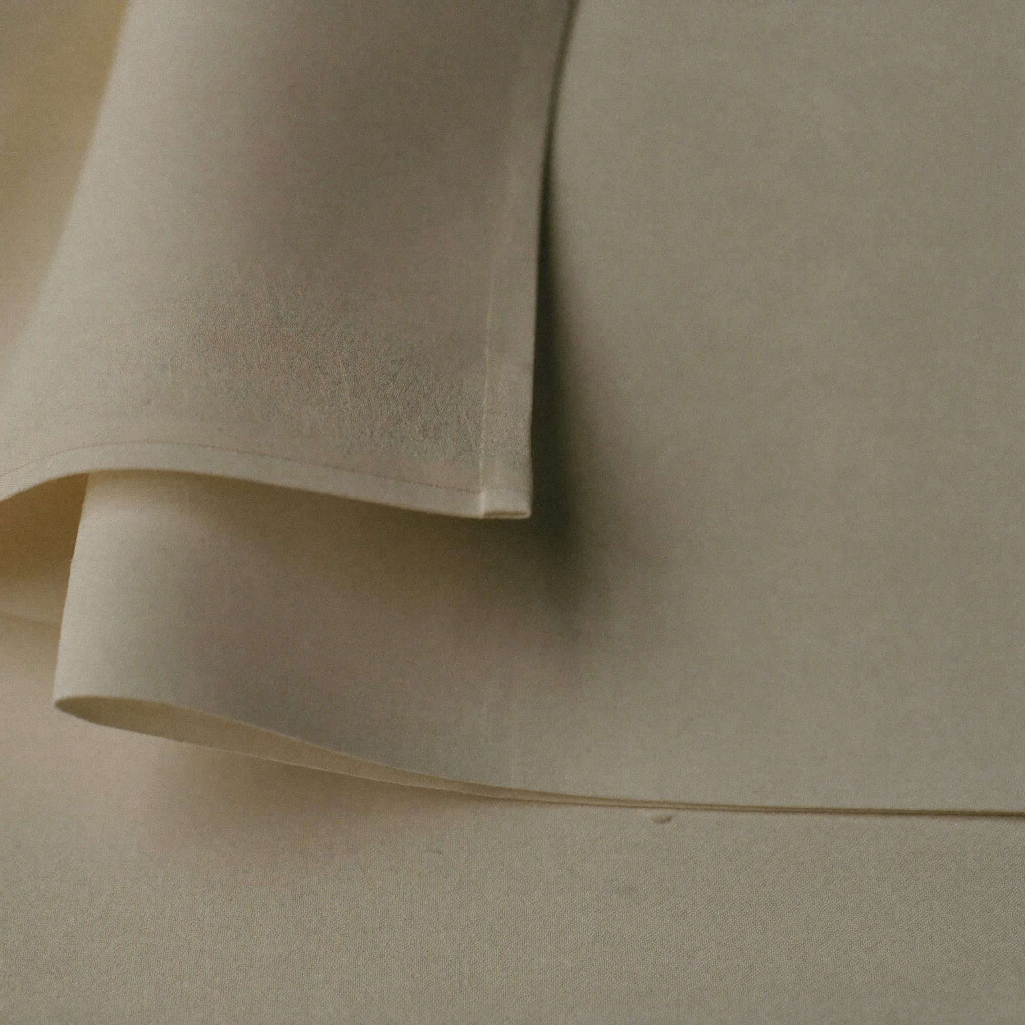 A close-up of folded ivory linen with a hand at the edge