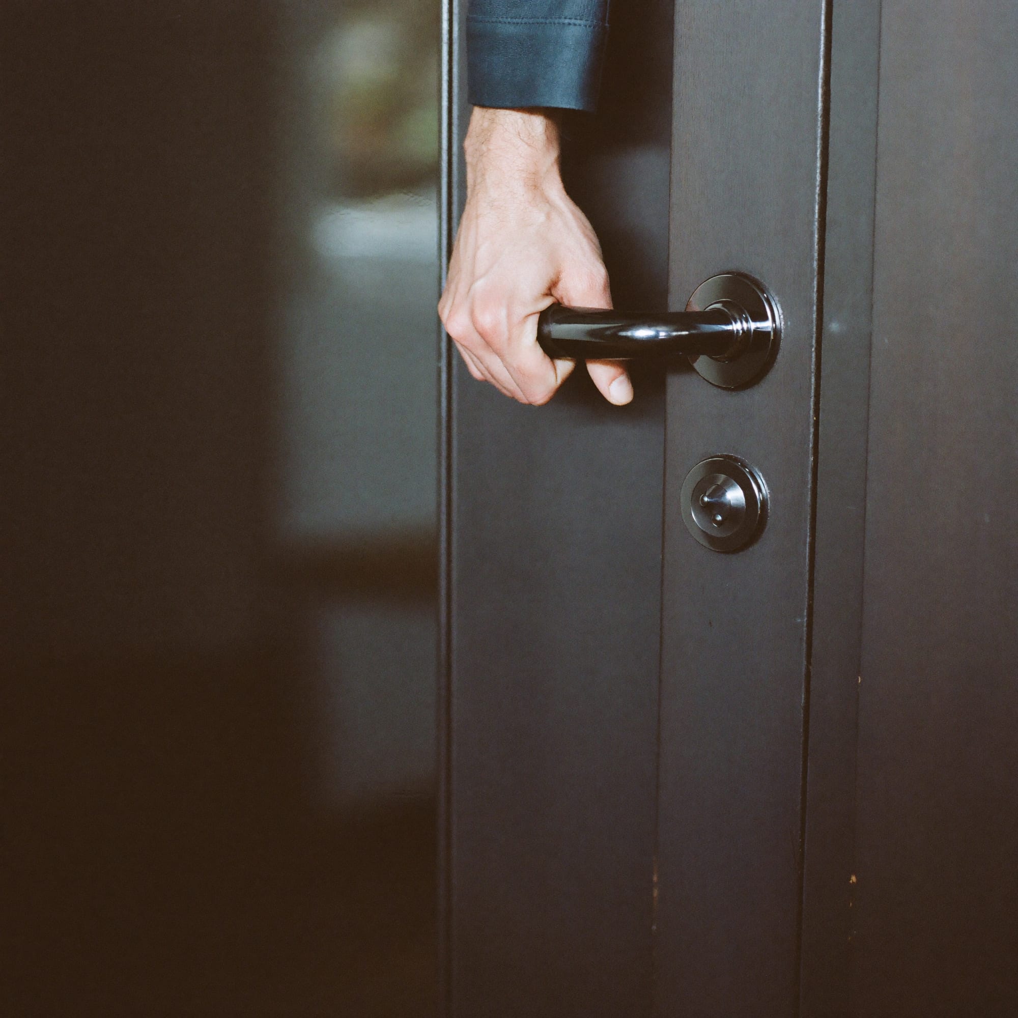 A gloved hand on a polished car door handle