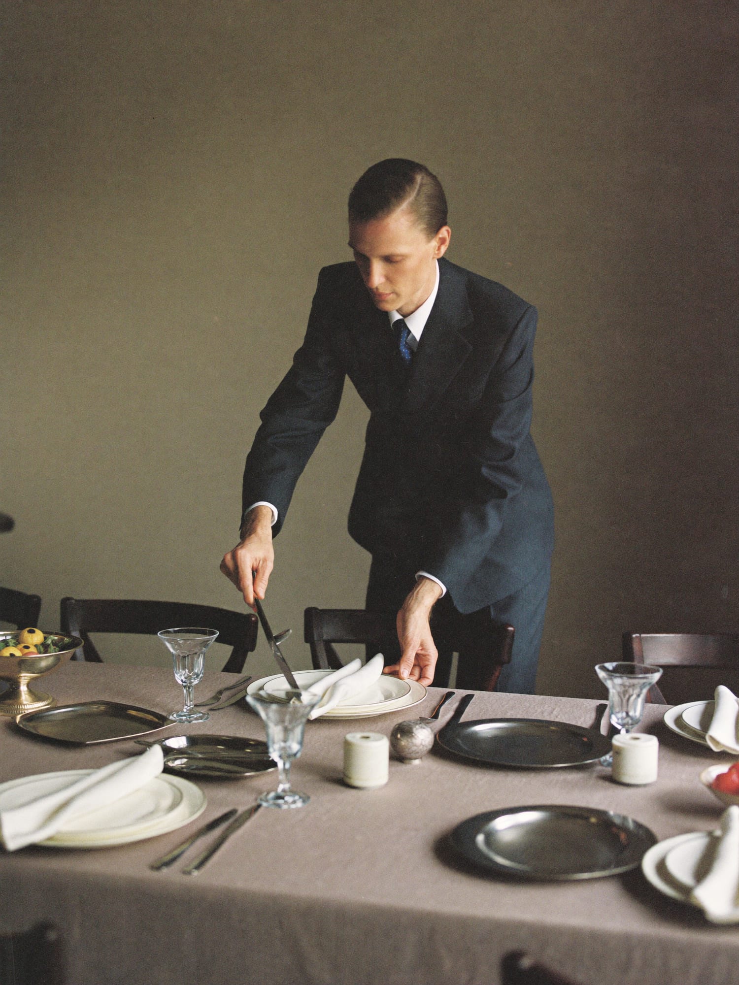 A butler adjusting a place setting at a long table