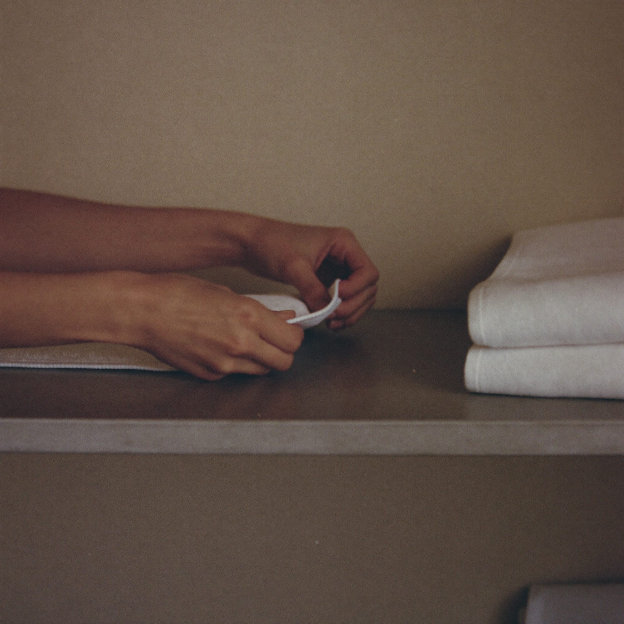 Hands folding a white towel on a linen shelf